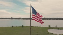 American flag on a flagpole by a river 