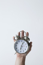 hand holding an alarm clock 