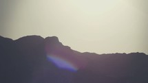 Sunrise over the silhouette of a mountain ridge.