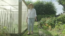 Steady cam view of a senior caucasian woman walking through her garden themes of retirement seniors gardening hobbies
