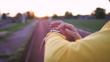 Fit woman use smart watch at sunset. Runner checking pulse on smartwatch on running workout. Modern technology and a healthy lifestyle. Athlete run woman check pulse on fitness bracelet.