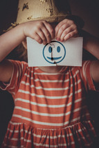 a child holding up a puzzle with a smiley face 