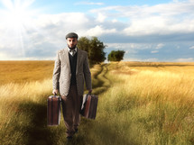 a man walking carrying luggage through a field 
