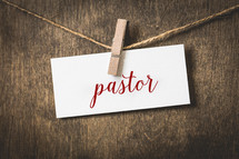 word pastor on white card stock hanging from a clothespin on a clothesline 