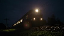 Train passing fast through a rural area, by night