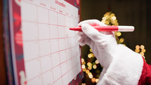 Santa Claus Marking Christmas Holidays on Calendar