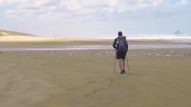 Men is walking on beach with flock of seagulls in New Zealand
