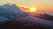 Time lapse of the sun setting over snowy mountains.
