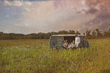 family sitting in an old van in a field
