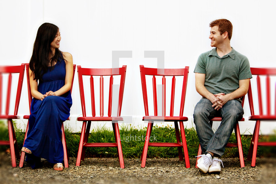 man and woman sitting in red chairs