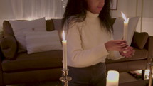 Woman lighting taper candles in a living room.
