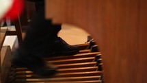 Closeup of an organist's feet skillfully playing foot pedals of a pipe organ in a catholic church during a service