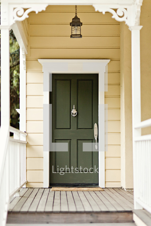 A wooden porch leading to a green front door.