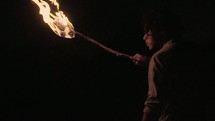 a man holding a torch standing in the darkness 