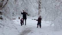father playing in the snow with his children 