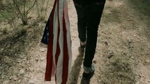 a man walking carrying an American flag 