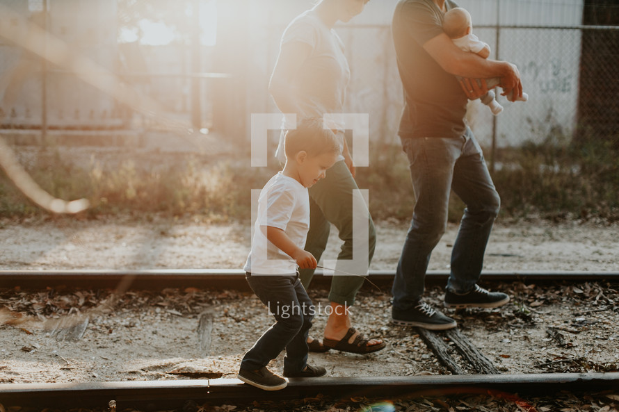 a young family walking on railroad tracks outdoors 