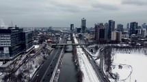 Aerial view of Don River and Don Valley Parkway in urban downtown Toronto on a cold winter day. Aircraft is moving backward across road while showing light vehicular traffic and a several bridges