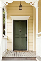 A wooden porch leading to a green front door.