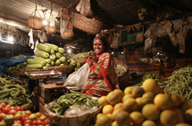 woman in India sitting with her hands together in a vegetable market
