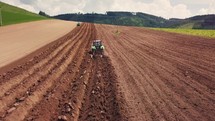 Tillage with a tractor, deep plowing cultivate in farm field and planting organic food potatoes in spring nature farmland
