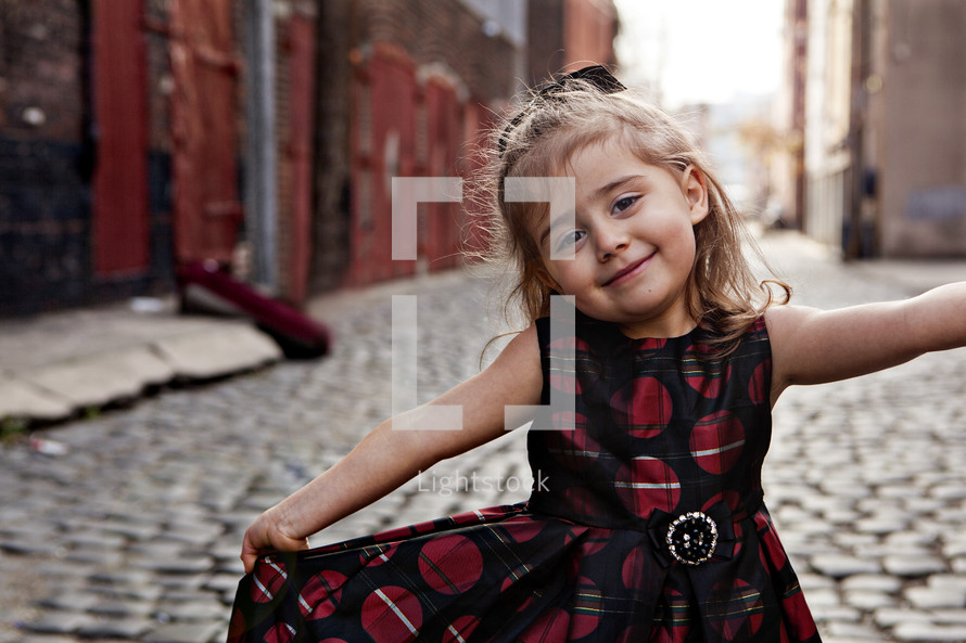 girl child in dress on a cobblestone street