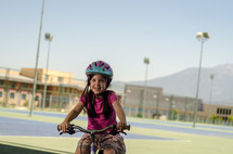 A young girl rides a bicycle near a school.