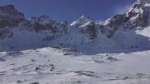 Panorama of winter alps mountains with mountain hut under rocky peak in cold sunny day outdoor tourism background
