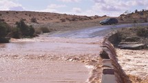 Muddy water of Flooded river flows over bridge in Africa country road after rain storm
