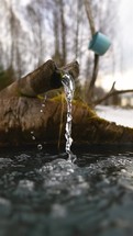 Slow motion of crystal clear drinking water from the spring at the nature well, Vertical video
