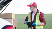 Delivery concept. Courier with parcel. Delivery man holding package in his hands while wearing face mask for coronavirus. Delivery man holding cardboard boxes in medical rubber gloves.