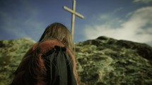 a woman standing on a mountaintop in front of a cross 