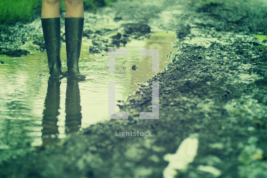 woman standing in a puddle with galoshes 
