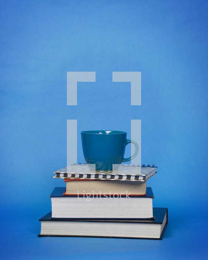 blue coffee cup on a stack of books 