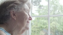 elderly woman looking out a window 
