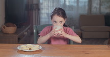 Little girl drinking a glass of milk at home.