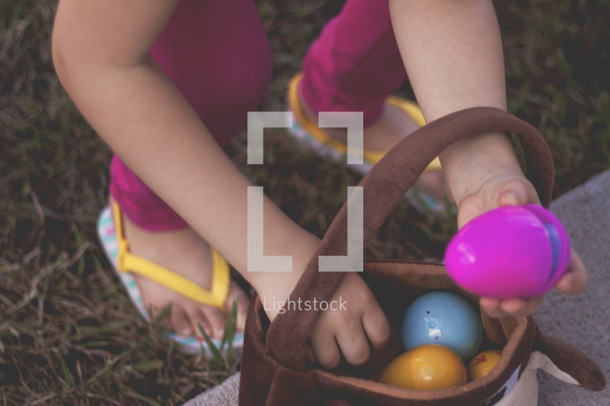a child putting an Easter egg in a basket 