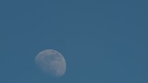 Full moon passing into the blue sky 