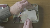 a man looking at old mementos in a tin 