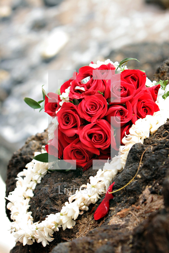 Bouquet of red roses and a lei on a rock