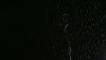 standing in falling rain at night 