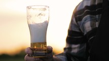 Senior man is drinking lager beer in outdoors. Tasty mildly alcoholic beer drink in a man's hand. Brewer pours fresh beer with foam into glass mug. Brewing concept.