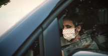 woman wearing a face mask driving a car 