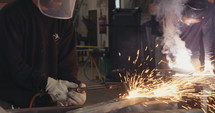 Welders using a tourch and welding metal parts in a workshop