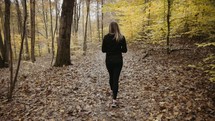 a woman walking in a forest in fall 