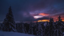 Fast clouds in winter forest in snowy alpine mountains at sunrise
