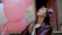Young happy woman with colorful white and pink balloons smiling and laughing. Slow motion.