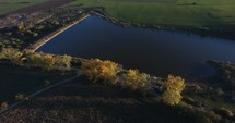 aerial view over farmland and manmade pond 