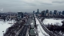 Aerial scene of Don Valley Parkway and Don River in urban downtown Toronto on a cold winter day. Aircraft is moving forward across road while showing moderate vehicular traffic and a series of bridges