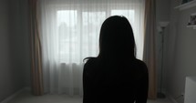 A Girl is Moving Towards the Window and Standing Beside it - Medium Close Up